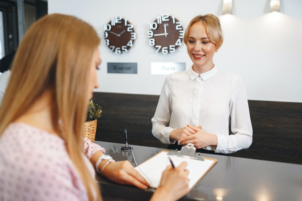 Blonde woman hotel guest checking-in at front desk in hotel